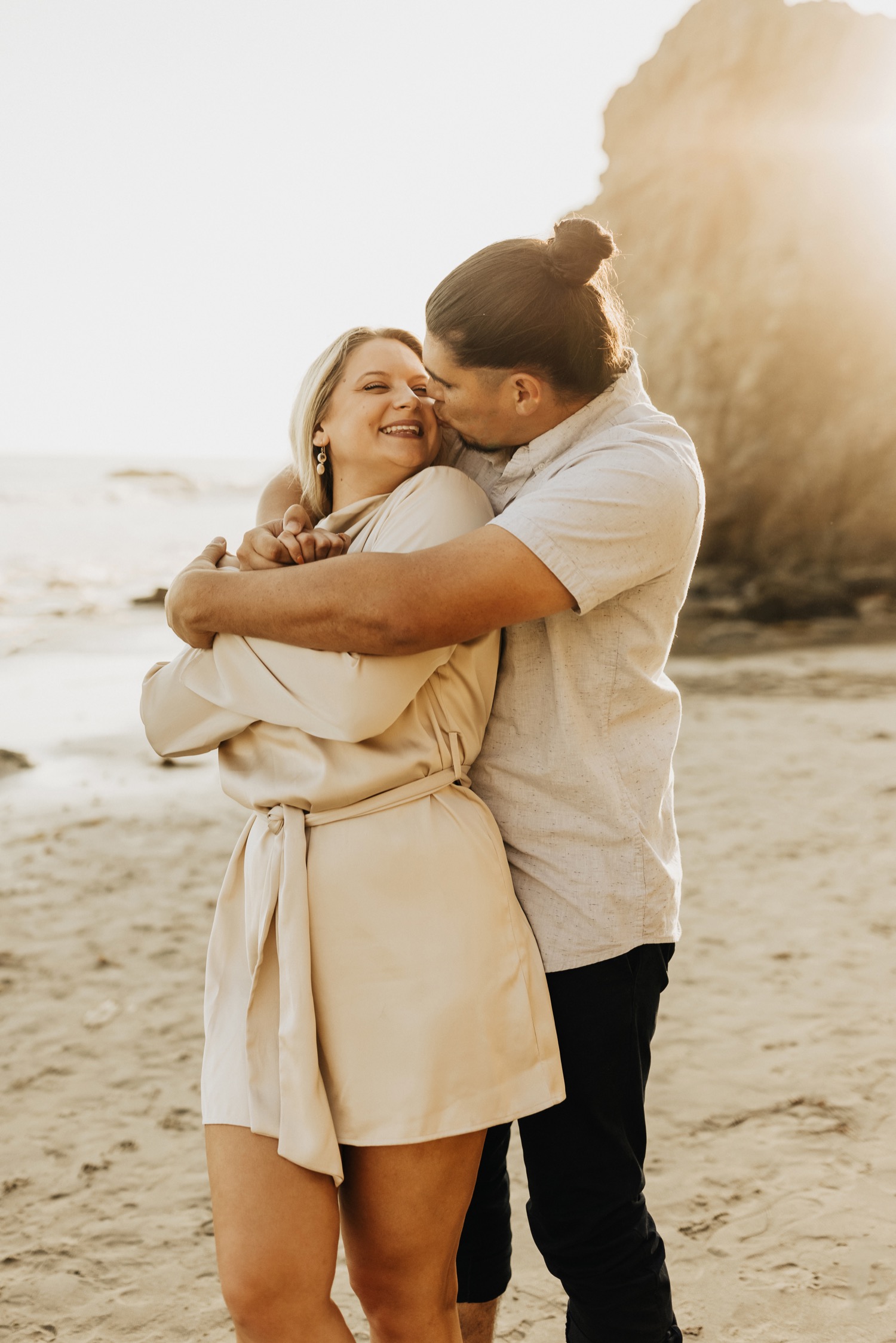 guy kissing girls cheek on beach in malibu