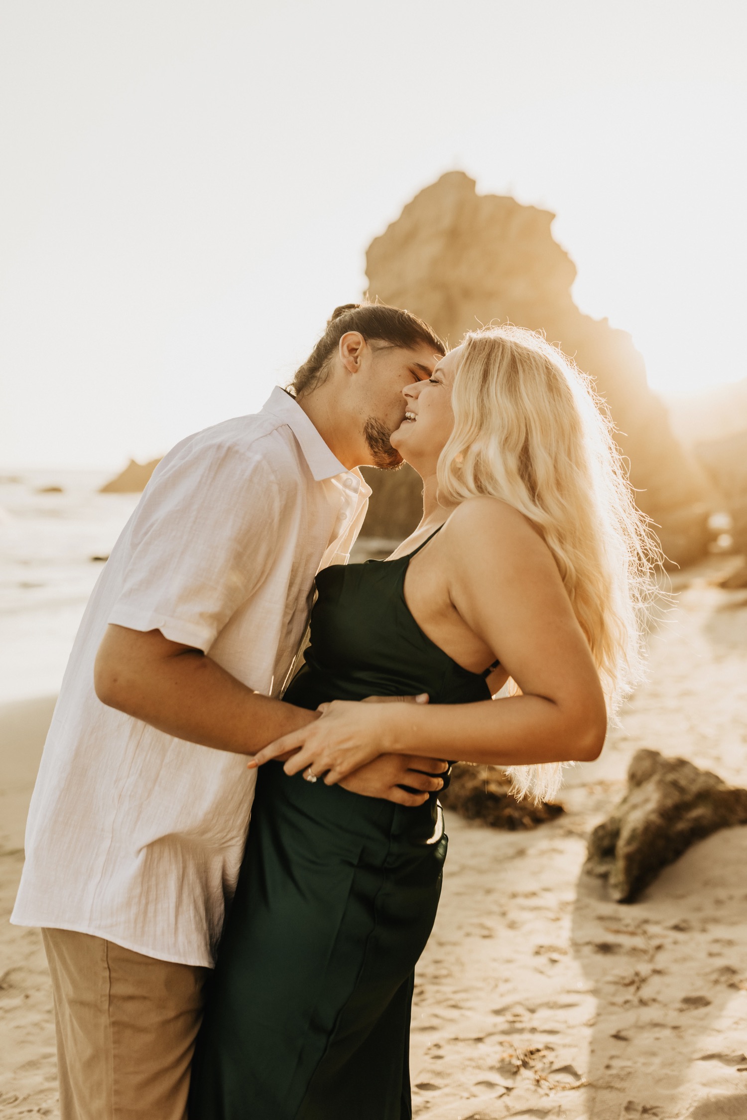 guy kissing girls cheek on beach in malibu